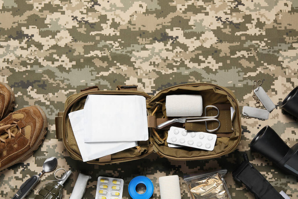 Flat lay composition with military first aid kit on camouflage fabric. Space for text - Photo, image