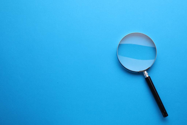 Magnifying glass on light blue background, top view. Space for text - Фото, зображення