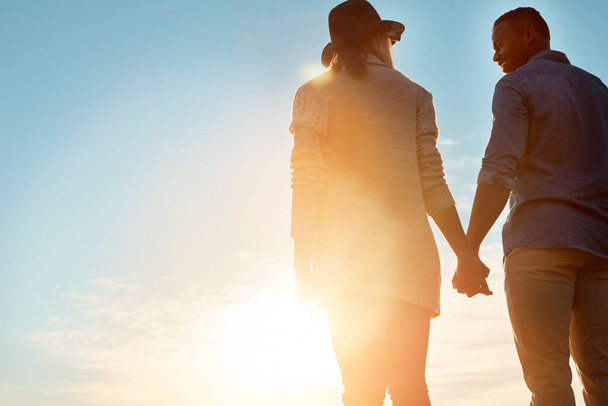 Нічого важливішого, ніж кохання. Знімок заднього виду щасливої молодої пари тримає руки на відкритому повітрі
 - Фото, зображення