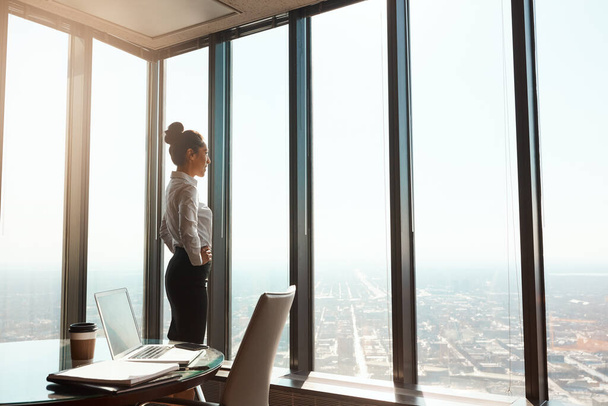 She made it to the top. an attractive young businesswoman standing with her hands on her hips in the office - 写真・画像