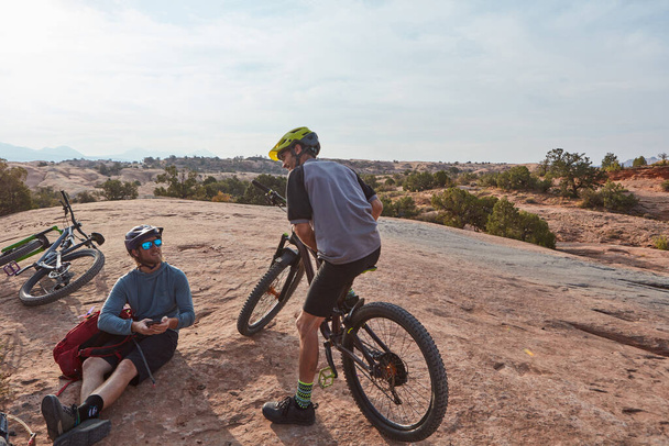 Não é apenas um hobby, é um estilo de vida. Tiro de comprimento total de dois homens atléticos fazendo uma pausa enquanto mountain bike pelo deserto - Foto, Imagem