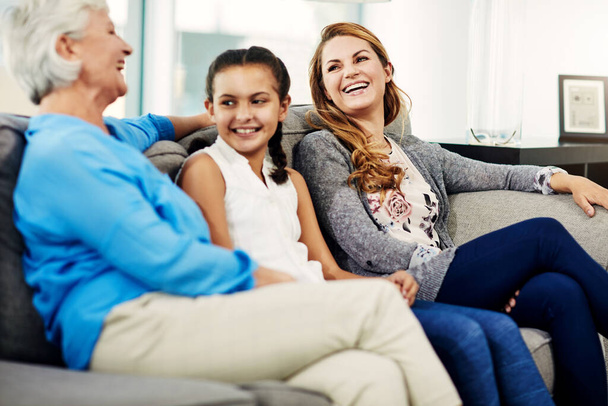 Viettää aikaa rakkaittensa kanssa. vanhempi nainen istuu sohvalla kotona tyttärensä ja tyttärentyttärensä kanssa - Valokuva, kuva