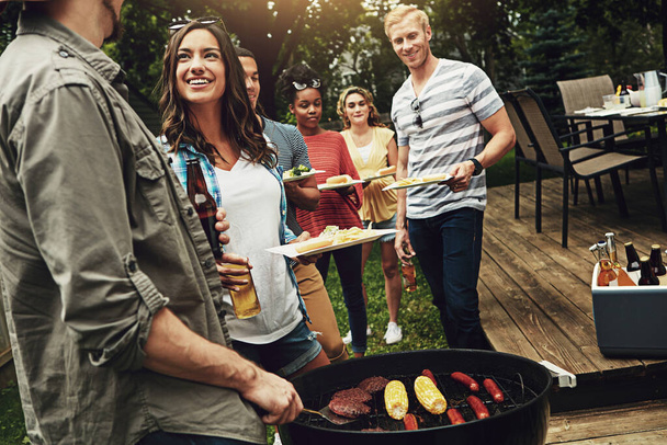 Ponerse al día en la cocina. un grupo de amigos haciendo una barbacoa en el patio - Foto, imagen