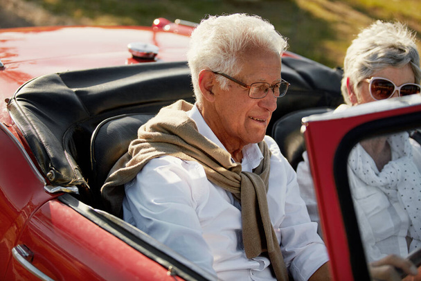 Το ταξίδι με το αυτοκίνητο είναι καλή ιδέα για συνταξιοδότηση. ένα ζευγάρι τελειόφοιτων πηγαίνει ένα οδικό ταξίδι - Φωτογραφία, εικόνα