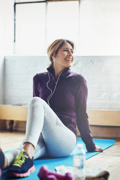 Fitness is een essentieel onderdeel van haar levensstijl. een aantrekkelijke jonge vrouw luisteren naar muziek tijdens het sporten thuis - Foto, afbeelding