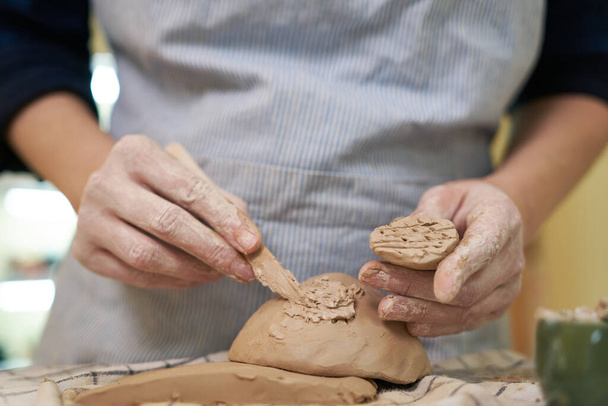 woman forming clay pot shape by hands, closeup in artistic studio. - Фото, изображение