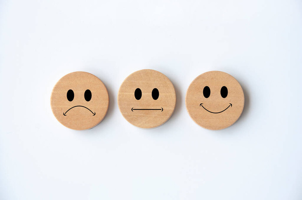 Caras emoticones felices, tristes y neutrales en círculo de madera con cubierta de fondo blanco. Comentarios de los clientes, satisfacción y evaluación y concepto. - Foto, imagen