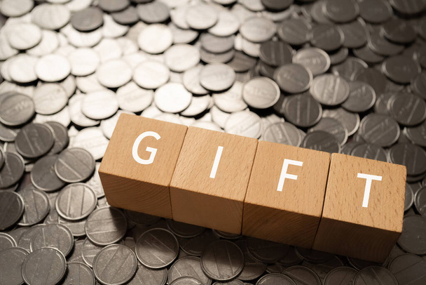 Wooden blocks with "GIFT" text of concept and coins. - Foto, Imagen