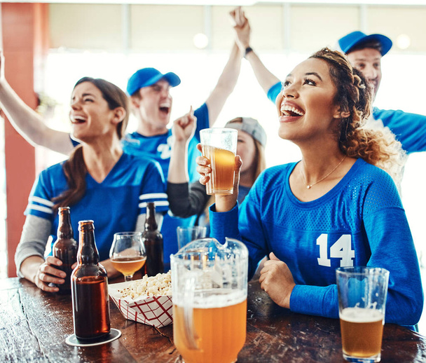 Ne manquez pas une minute de l'action. un groupe d'amis qui applaudissent en regardant un match de sport dans un bar - Photo, image