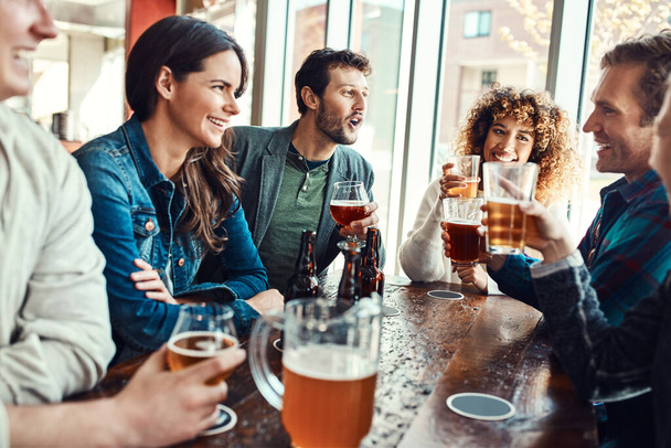 Were always down for a beer and good company. young people having beers at a bar - Foto, Imagem