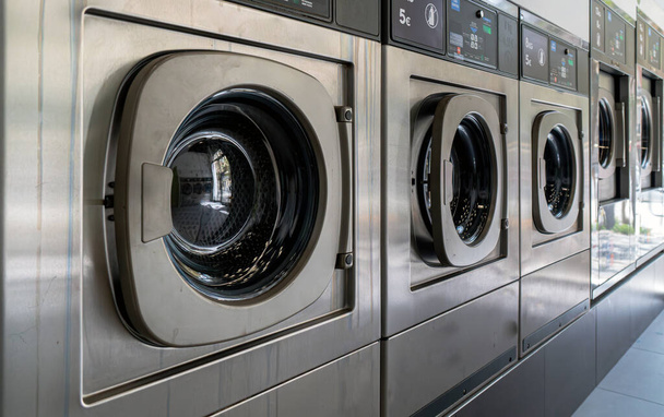 Lave-linge dans une blanchisserie urbaine pour laver et sécher les vêtements, les draps et les nappes en rangée avec les portes fermées - Photo, image