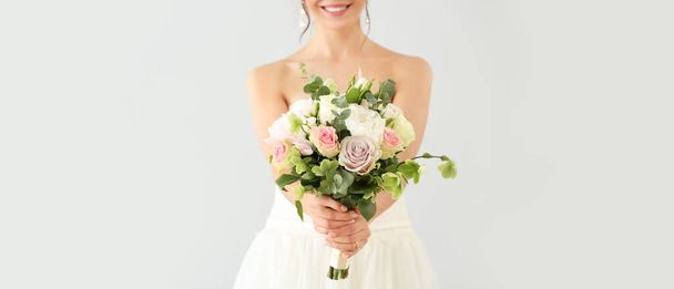 Beautiful young bride with bouquet of flowers on light background - Foto, Imagem
