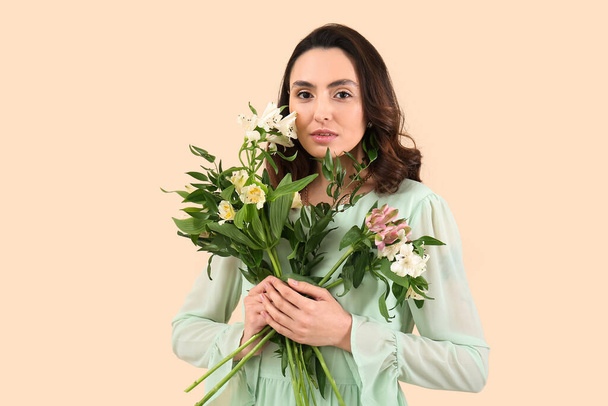Young woman in dress with alstroemeria flowers on beige background - Foto, Imagen