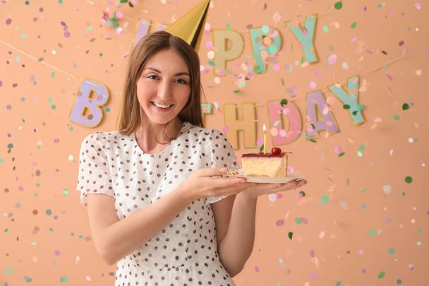 Happy young woman with piece of Birthday cake on beige background - Фото, зображення
