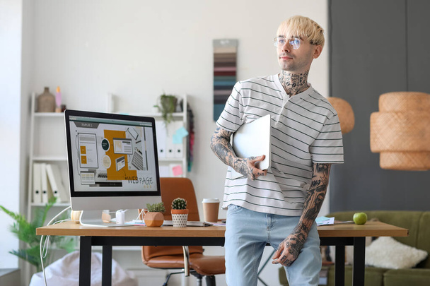 Γραφίστας με τατουάζ και φορητό υπολογιστή στο γραφείο - Φωτογραφία, εικόνα