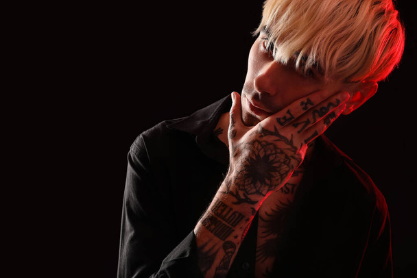Tattooed young man on dark background, closeup - Valokuva, kuva