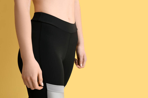 Sporty young woman in leggings on yellow background, closeup - Fotoğraf, Görsel