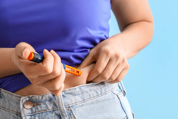 Woman with diabetes using lancet pen  on light blue background, closeup - 写真・画像