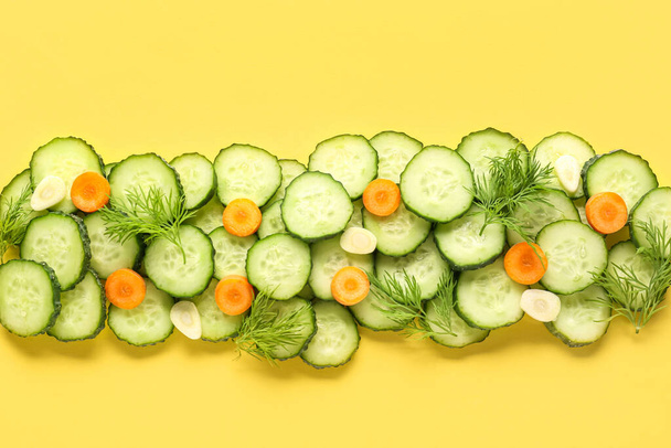 Snijdt komkommer met dille en wortel op gele achtergrond - Foto, afbeelding
