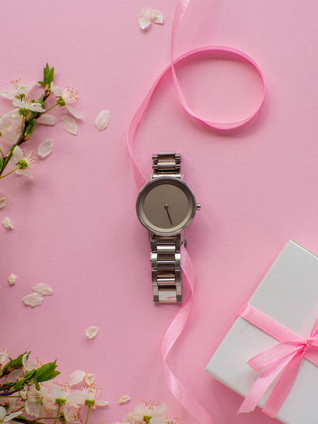 Womens hand watch on pink background with cherry flowers and copy space. Womens, Valentines and Mothers Day gift. Concept of beauty, elegance and femininity. Buying birthday gifts online.  - Фото, зображення