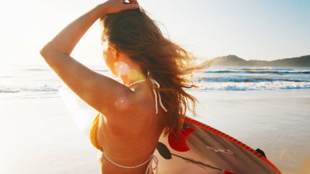 Woman surfer walks with surfing board on the tropical beach - Foto, Imagen