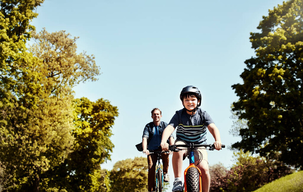 Znaleźli coś fajnego do zrobienia razem. młody chłopiec i jego ojciec jadący razem na rowerach - Zdjęcie, obraz