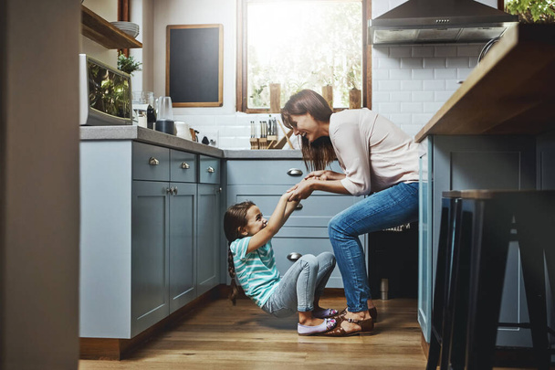 Wypełniała dzieciństwo zabawą. matka bawiąca się z córeczką w kuchni w domu - Zdjęcie, obraz