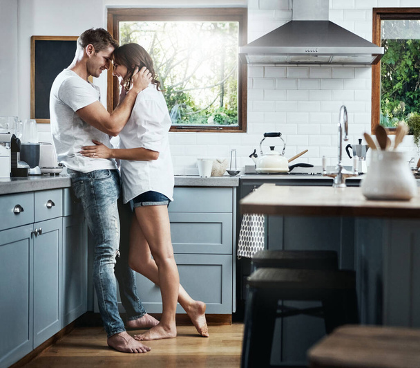 Meine Tage sind mit dir hundertmal heller. Ein liebevolles junges Paar, das zu Hause zusammen in der Küche steht - Foto, Bild