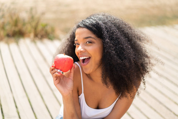 Joven mujer afroamericana al aire libre comiendo una manzana - Foto, Imagen