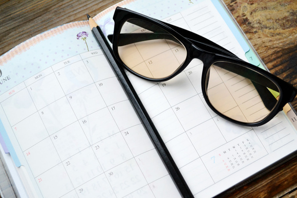 Un planificateur quotidien rétro vide avec crayon noir et lunettes de lecture
 - Photo, image