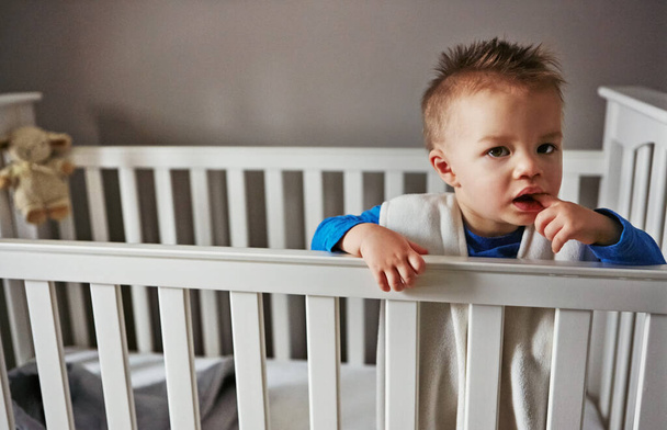 I dont find being trapped funny...a cute little baby boy standing in his cot - Photo, image