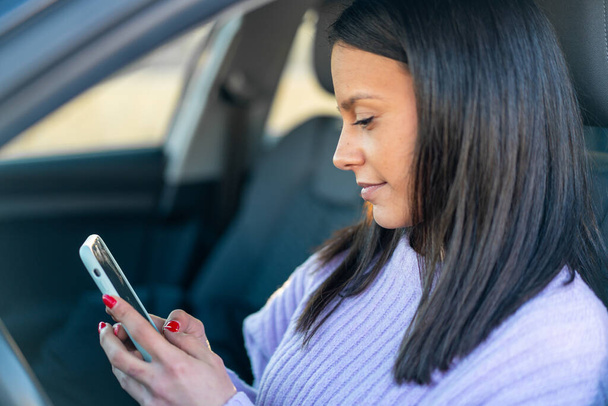Mujer joven al aire libre dentro de un coche con teléfono móvil - Foto, imagen