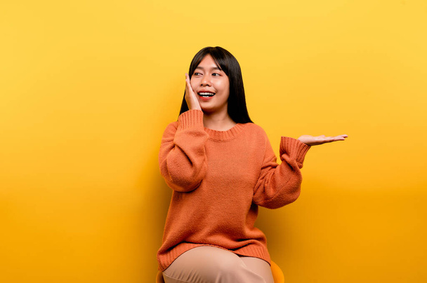 asian girl Pretty wearing an orange casual dress. yellow background Celebrate the victory with a happy smile and the winner's expression with a raised hand. happy expression - Photo, Image
