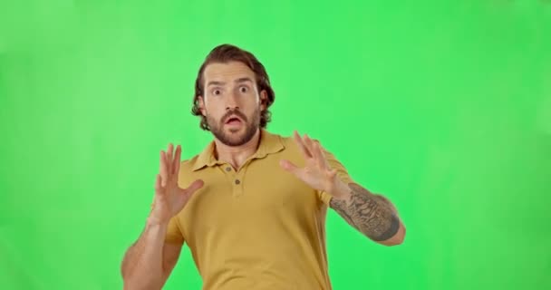 Shock, fear and a scared man on a green screen background in studio getting frightened or startled. Horror portrait, scary and reaction with a handsome young male person in danger on chromakey mockup. - Footage, Video