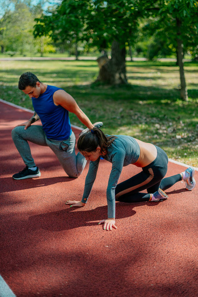 Two lovely friends working out on a red sports track, outdoors - Foto, imagen