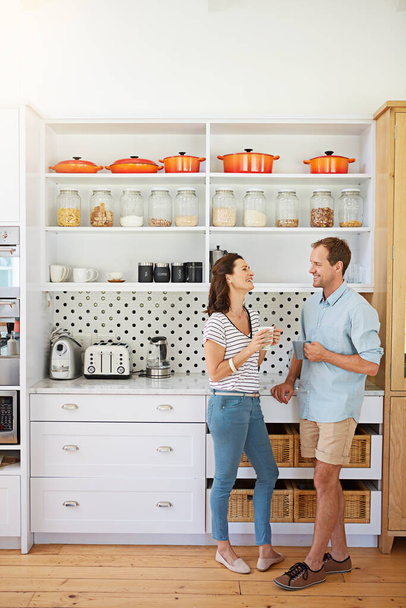 Знайдіть когось, хто наповнює ваше життя сміхом. щаслива подружня пара насолоджується чашкою кави разом на своїй кухні вдома
 - Фото, зображення