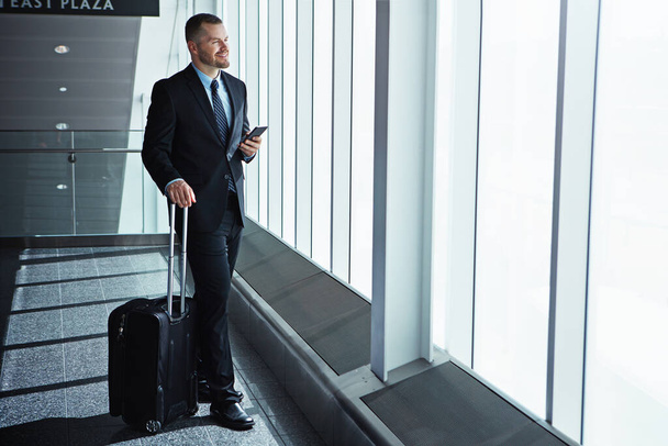 Zijn vooruitzichten zien er goed uit. een zakenman die tijdens een zakenreis over een luchthaven loopt - Foto, afbeelding