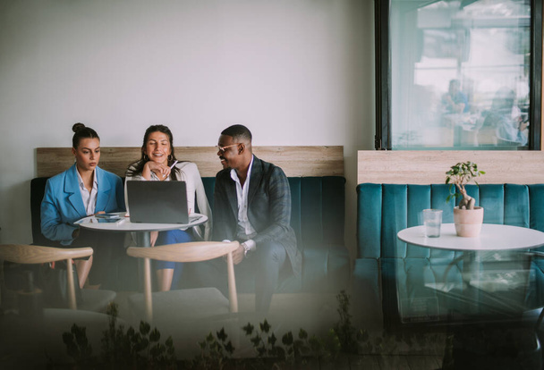 Три бізнес-колеги сміялися, сидячи в кафе
 - Фото, зображення