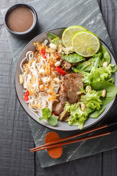 Vietnamees rundvlees Noodle Salad Pho Tron close-up op de plaat op de houten tafel. Verticaal bovenaanzicht van bovenaf - Foto, afbeelding