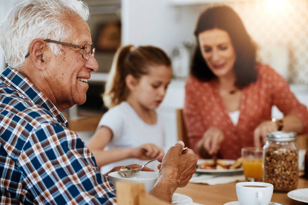 C'est un bon petit déjeuner. un homme âgé qui prend son petit déjeuner avec sa famille à la maison - Photo, image