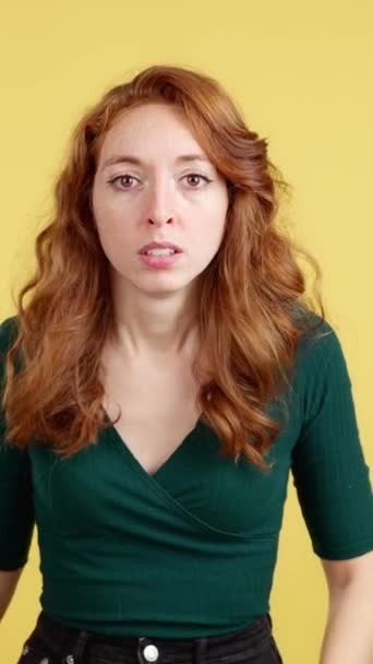 roodharige vrouw gebaren met de handen in angst in studio met gele achtergrond - Video