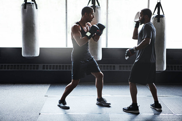 Hij heeft het potentieel om iets geweldigs te zijn. een mannelijke bokser oefent zijn bewegingen met zijn coach - Foto, afbeelding