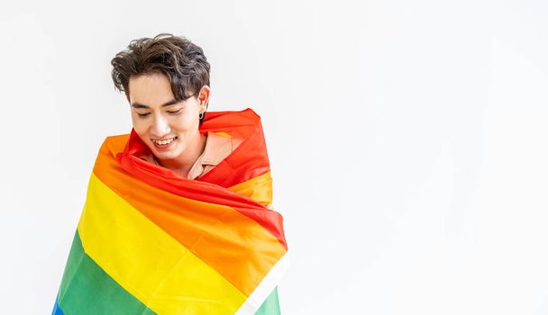 Porträt eines vor der Kamera lächelnden Transgenders oder Schwulen mit lgbt-Flagge auf weißem Hintergrund mit Kopierraum. Menschen Lifestyle Mode lgbtq Konzept - Foto, Bild