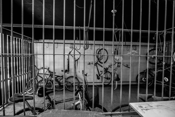 A grayscale shot of a room filled with old bicycles hanging from the wall - Photo, image
