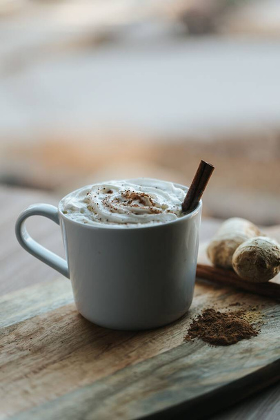 A vertical shot of a cup of hot chocolate on the wooden background - Zdjęcie, obraz
