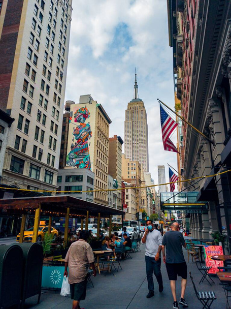 A beautiful view of a crowded street with a view of the Empire State Building and the Guilded Lady - 写真・画像