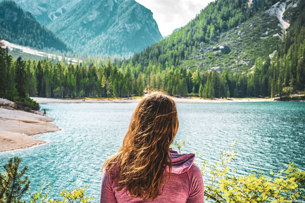 A young caucasian lady admiring the view of Baires Lake in the Dolomite mountains, South Tirol, Italy, Europe - Foto, Imagem