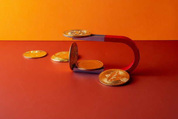 A closeup shot of a magnet and coins on a red and orange background - Photo, Image
