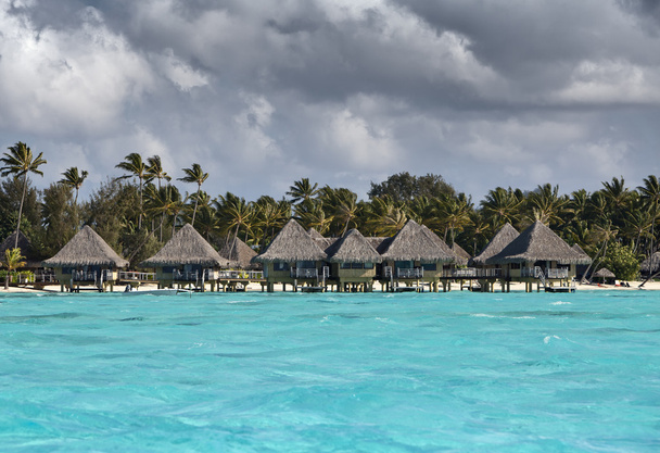 Typisch Polynesisch landschap - zeekust met palmbomen en huisjes aan het water - Foto, afbeelding