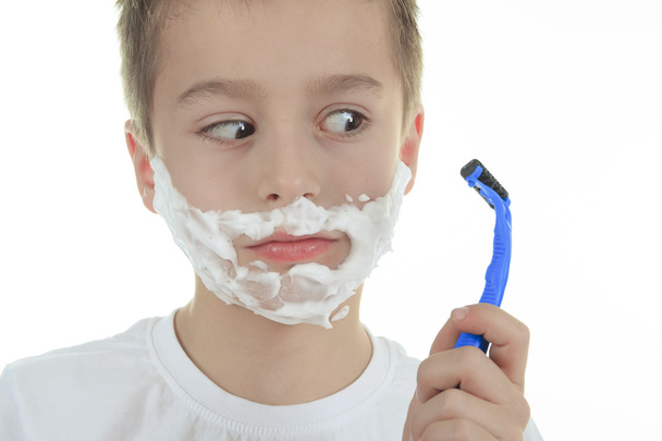 playful little young boy shaving face over white background - 写真・画像